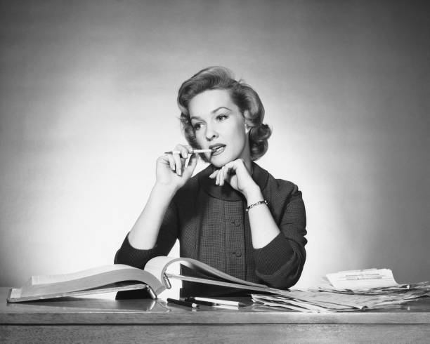 Woman chewing on pencil, book open in front of her  secretary photos stock pictures, royalty-free photos & images