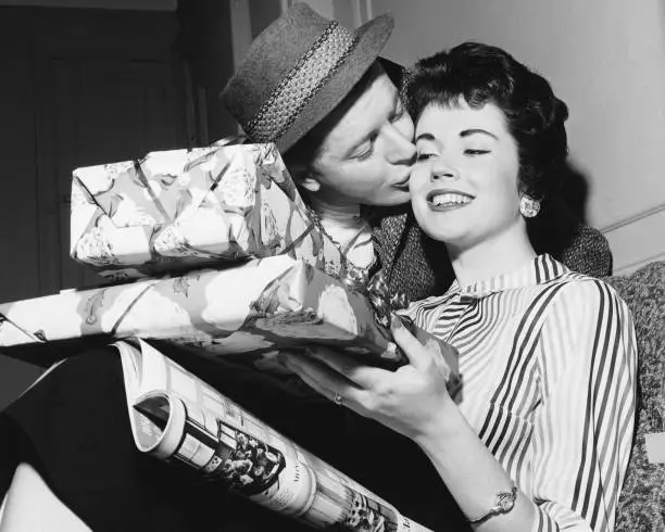 Photo of Husband kissing wife with armful of gifts