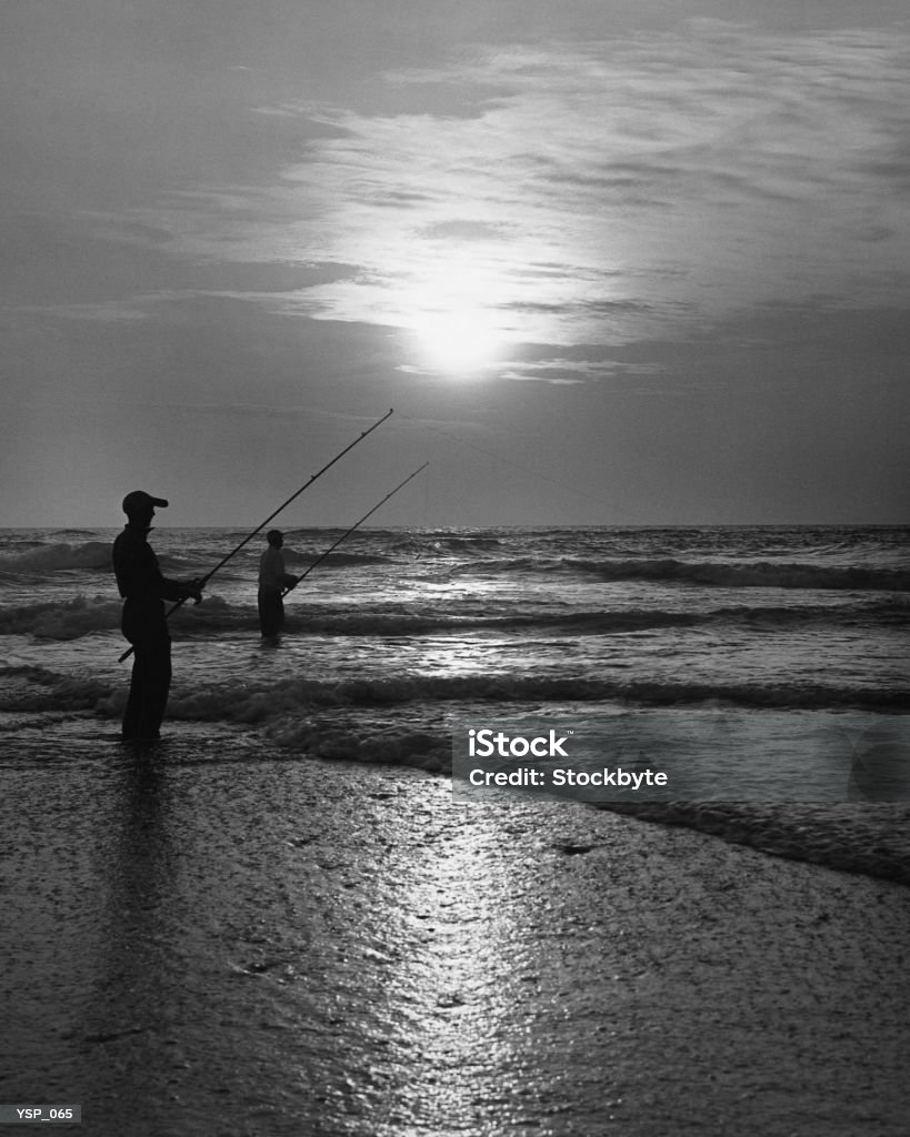 Zwei Mann Angeln vom Ufer bei Sonnenuntergang - Lizenzfrei Schwarzweiß-Bild Stock-Foto