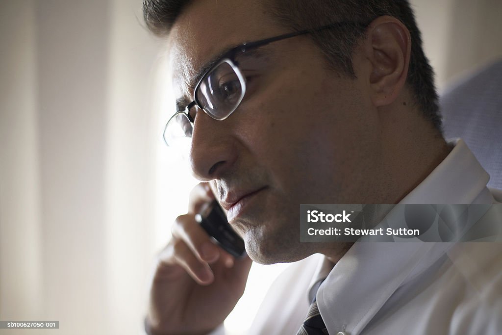 Mid adult business man wearing spectacles using mobile phone, sitting in airplane  30-39 Years Stock Photo