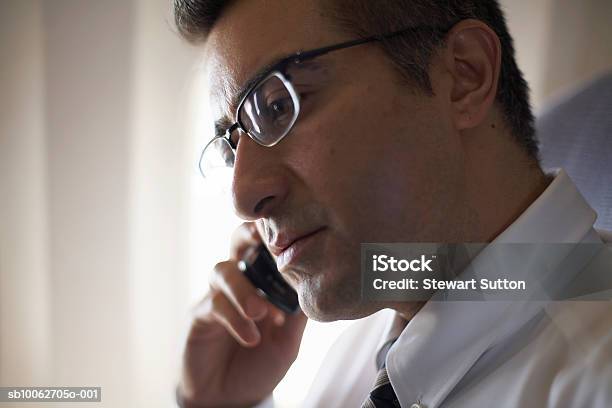 Mid Adult Business Man Wearing Spectacles Using Mobile Phone Sitting In Airplane Stock Photo - Download Image Now