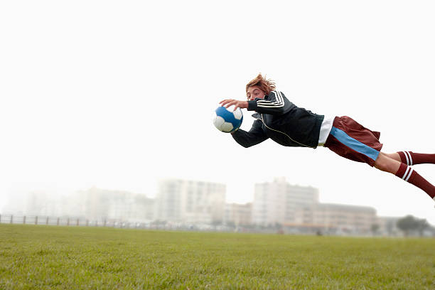 teenage boy (14-15) diving to catch football - goalie soccer soccer player teenage boys стоковые фото и изображения