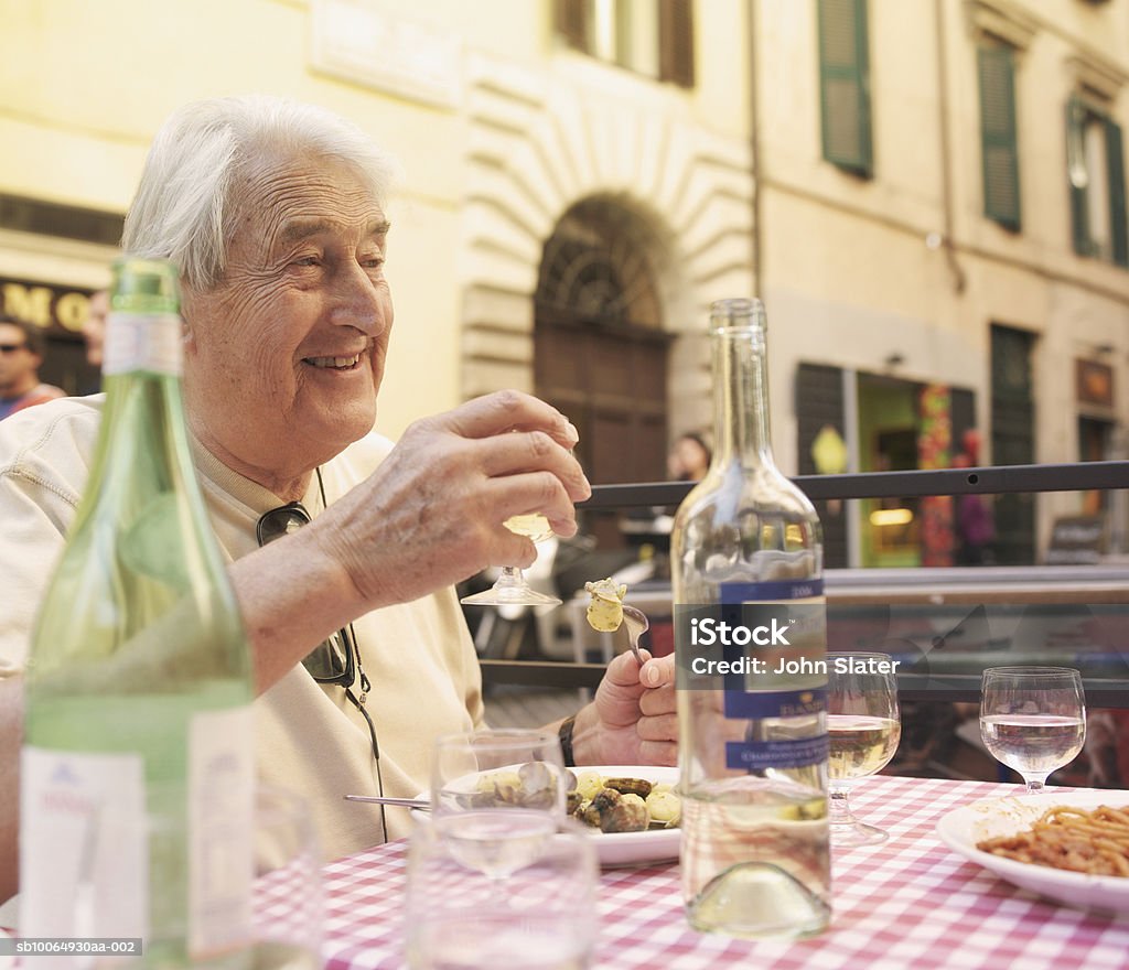 Senior man drinking wine at restaurant, smiling - Photo de Aliment libre de droits