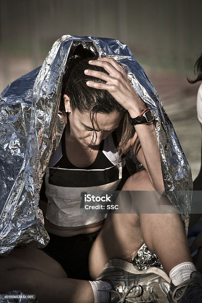 Female athlete sitting with head in hands - Foto de stock de Agotamiento libre de derechos