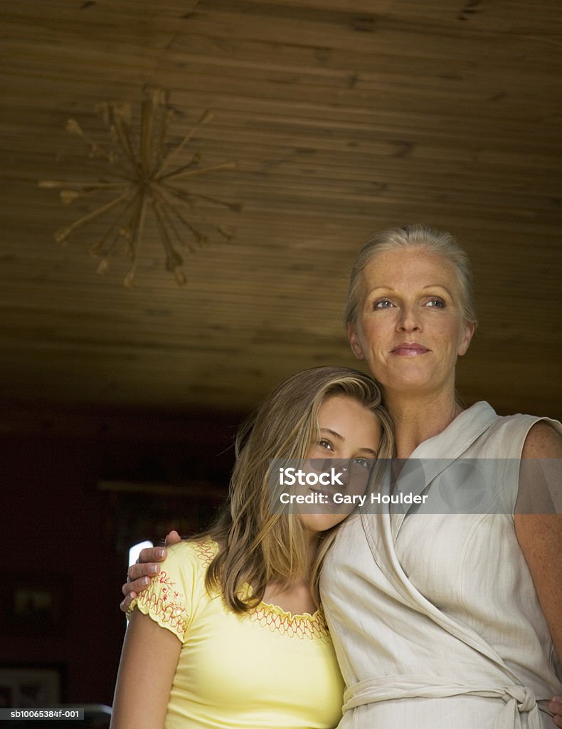 Mother and daughter (12-13) embracing, low angle view  12-13 Years Stock Photo