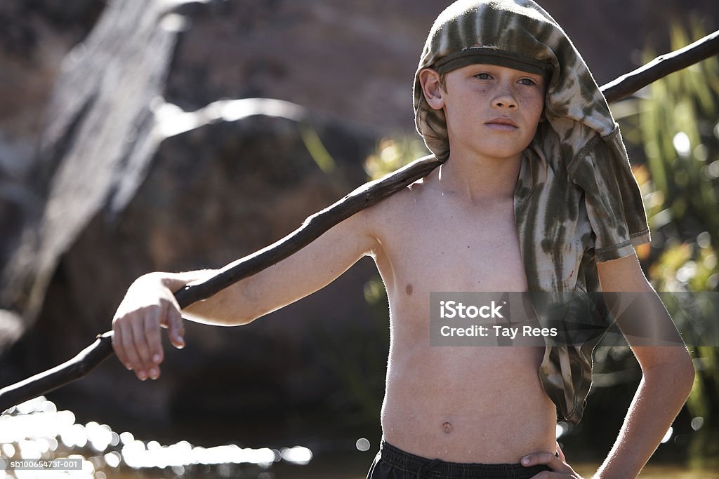 Boy (10 a 13) de pie con sujeción polos, mano sobre la cadera - Foto de stock de 12-13 años libre de derechos