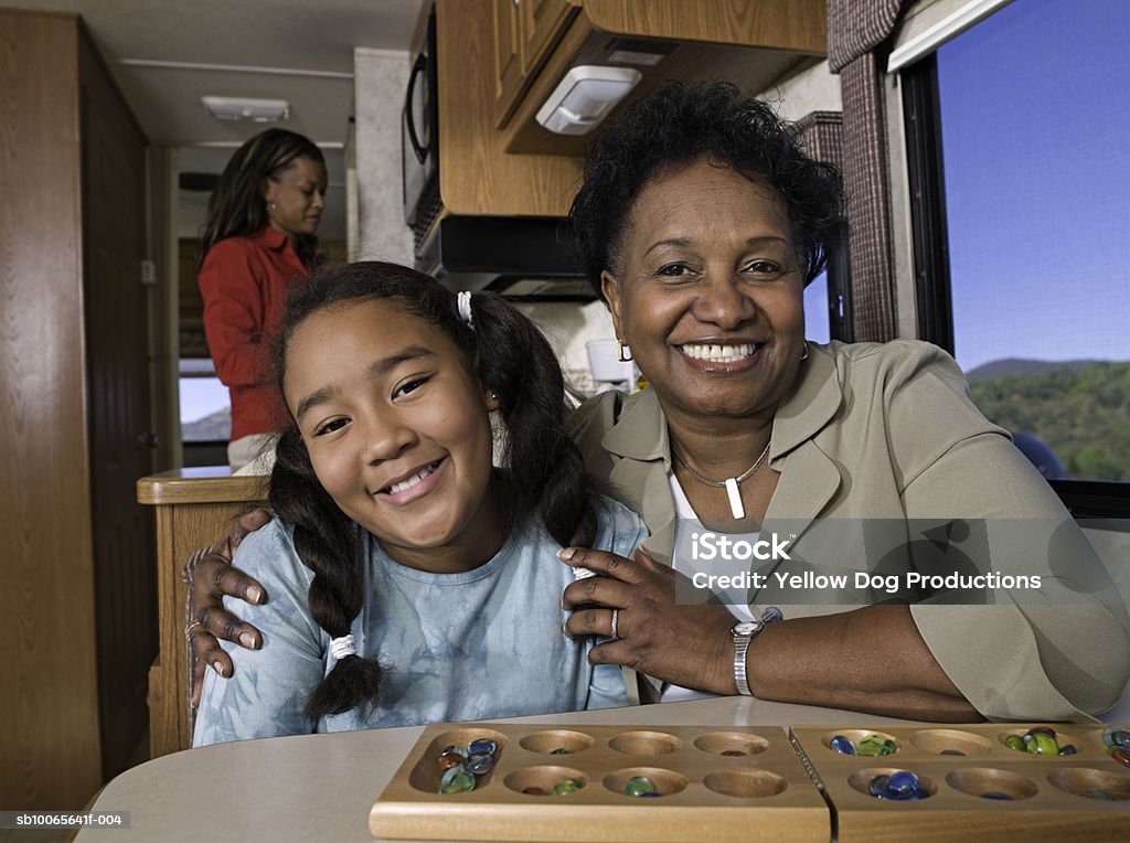 Grandmother with children (10-13) mother cooking in background in motorhome - Foto de stock de Africano-americano libre de derechos