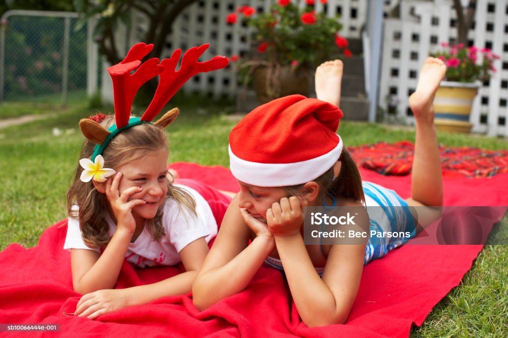 Niñas (7-9) usando sombrero de Navidad, caer en manta en prado - Foto de stock de 6-7 años libre de derechos