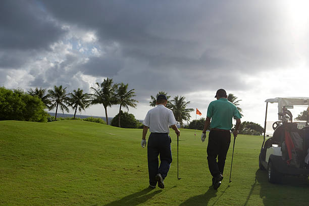 dois homens em campo de golfe a pé vista traseira - saipan - fotografias e filmes do acervo