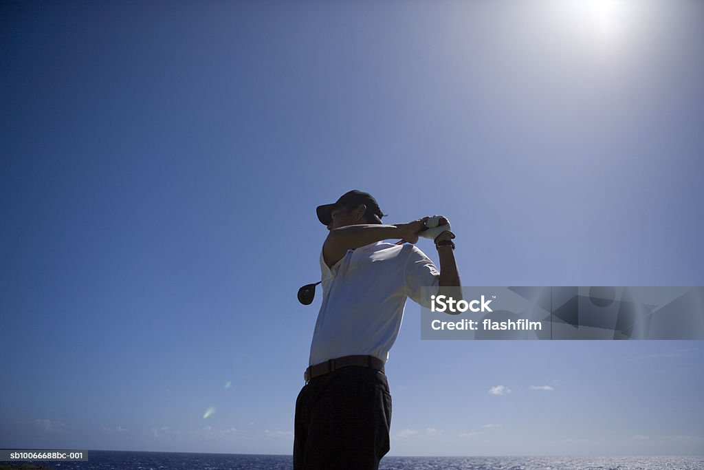 Man swinging golf club, low angle view Saipan, USA Adult Stock Photo