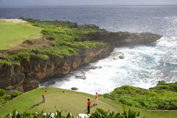tres hombres jugando al golf junto al mar; vista elevada - saipan fotografías e imágenes de stock