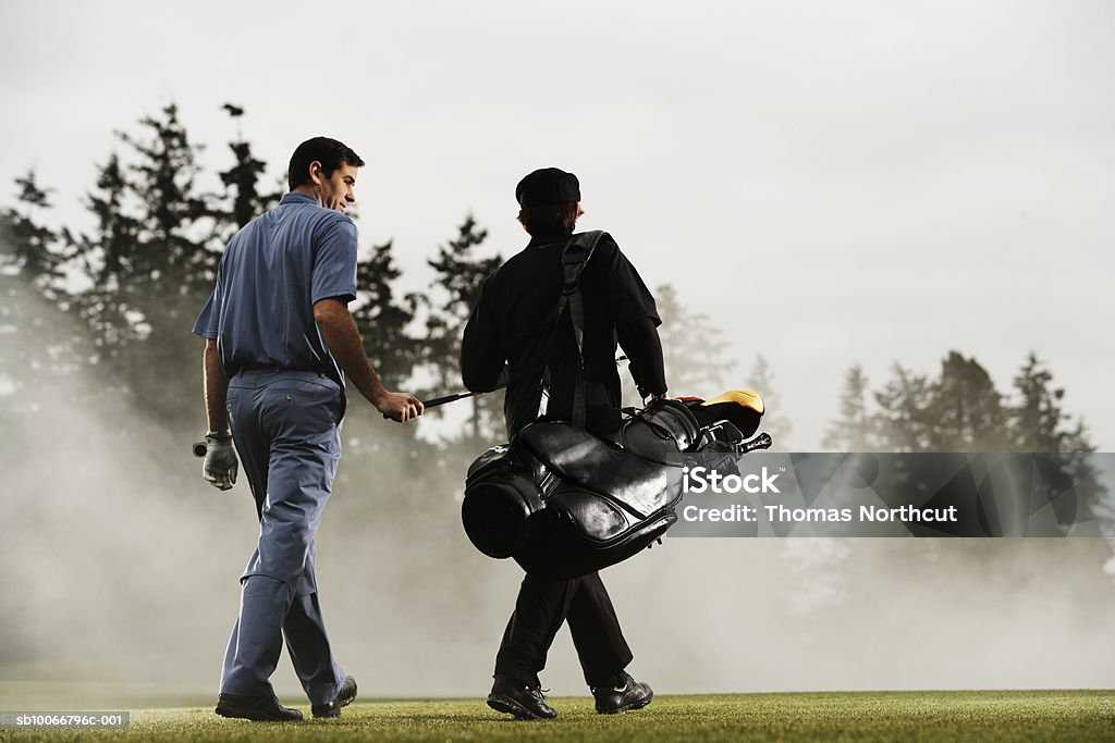 Two golf players walking in golf course, rear view  Golfer Stock Photo