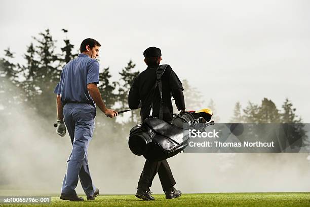 Two Golf Players Walking In Golf Course Rear View Stock Photo - Download Image Now - Golfer, Holding, Talking