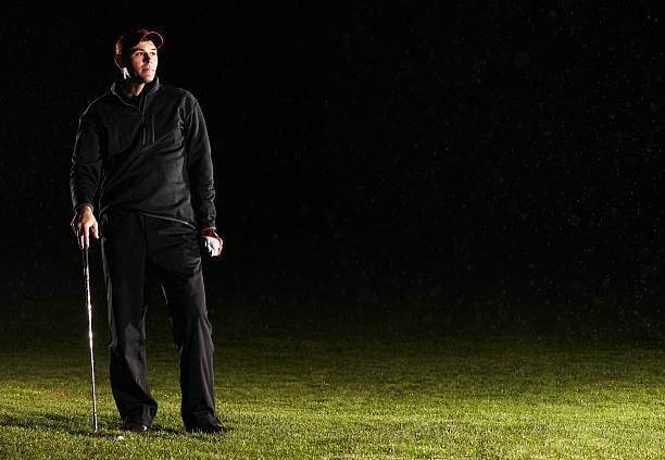 Male golf player standing in golf course, looking away  night golf stock pictures, royalty-free photos & images