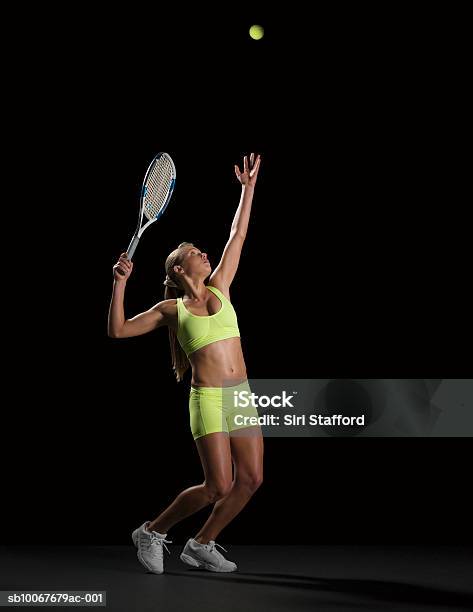 Female Tennis Player Serving Ball Studio Shot Stock Photo - Download Image Now - Tennis, Serving - Sport, Black Background