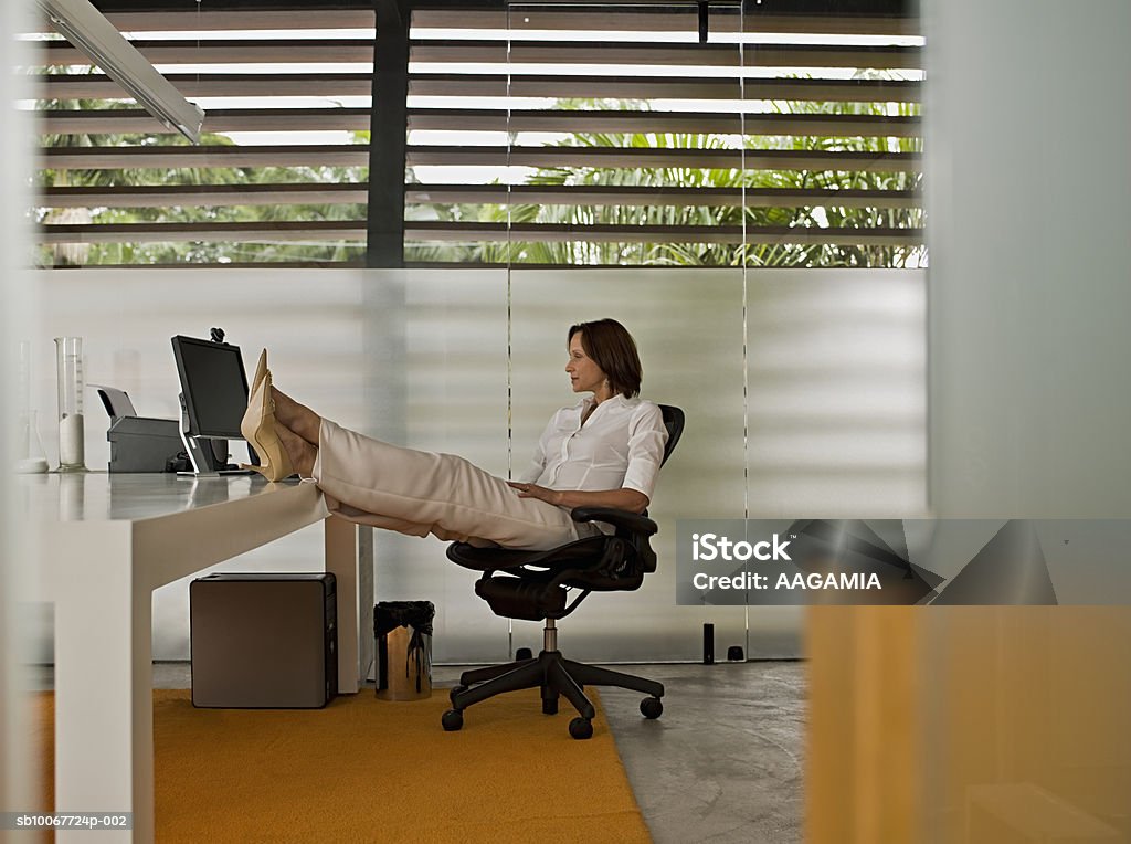 Businesswoman with feet up on desk - Photo de 55-59 ans libre de droits