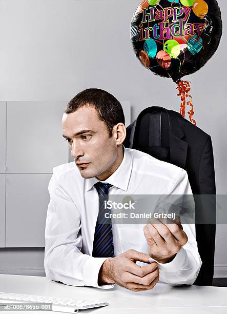 Business Man Sitting Behind Desk With Baloon Tied To Chair Stockfoto und mehr Bilder von 30-34 Jahre