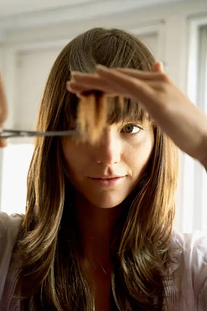 Photo of Woman cutting hair with scissors, close-up