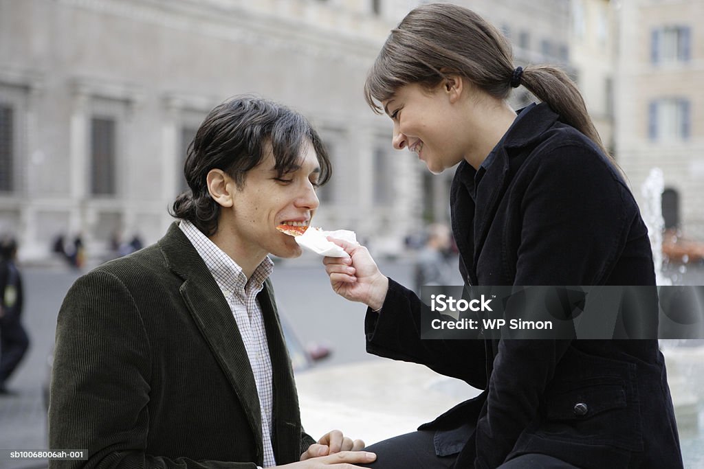 Couple sharing slice of pizza outdoors - Foto de stock de 20-24 años libre de derechos