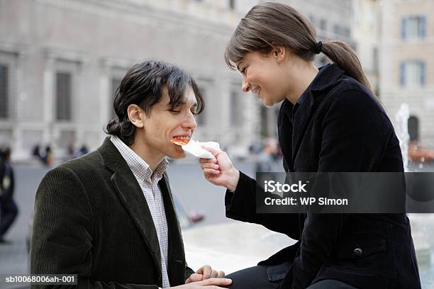 Couple Sharing Slice Of Pizza Outdoors Foto de stock y más banco de imágenes de 20-24 años - 20-24 años, 30-34 años, Abierto