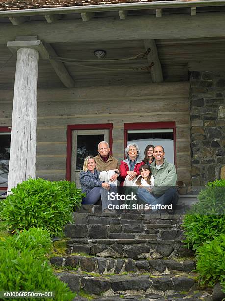 Three Generation Family Sitting On Steps In Front Of House Smiling Portrait Stockfoto en meer beelden van Voor