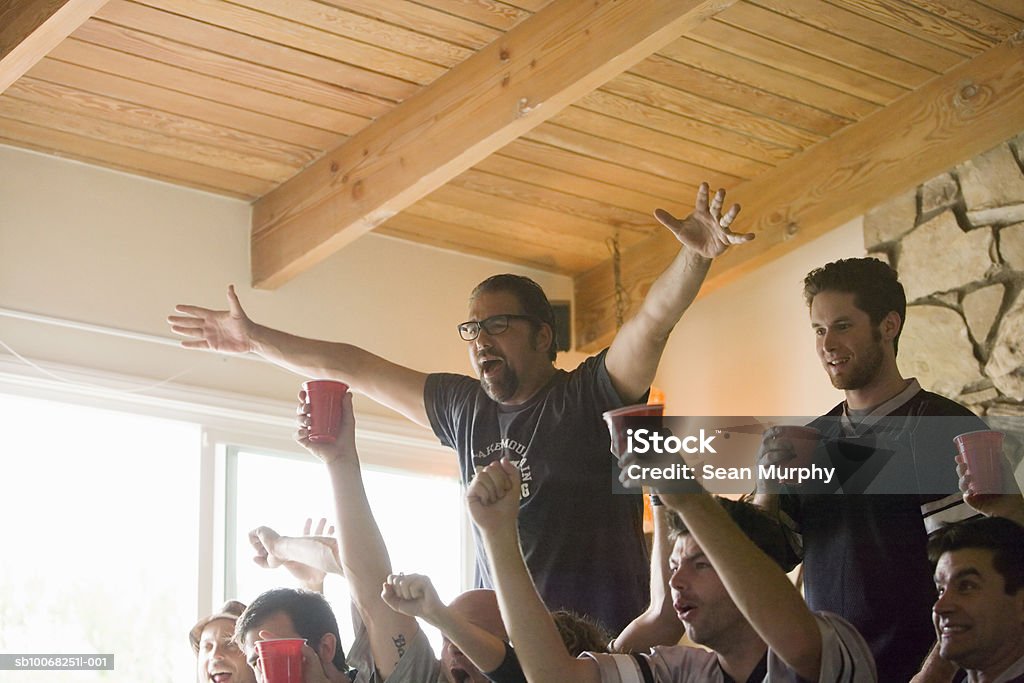 Group of friends watching tv, gesturing and yelling USA, California, Los Angeles Cheering Stock Photo