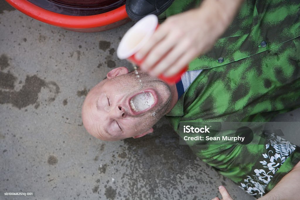 Man lying on ground having beer poured into mouth USA, California, Los Angeles 35-39 Years Stock Photo
