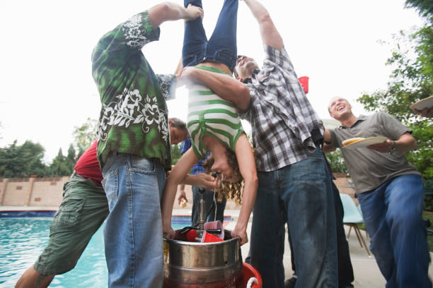 grupo de homens segurando mulher de cabeça para baixo para fazer'keg stand' - homem com a cabeça para baixo em uma reunião - fotografias e filmes do acervo