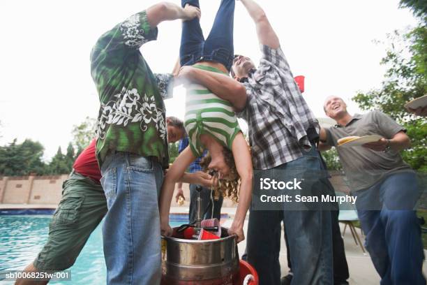 Grupo De Homens Segurando Mulher De Cabeça Para Baixo Para Fazerkeg Stand - Fotografias de stock e mais imagens de Barrilete