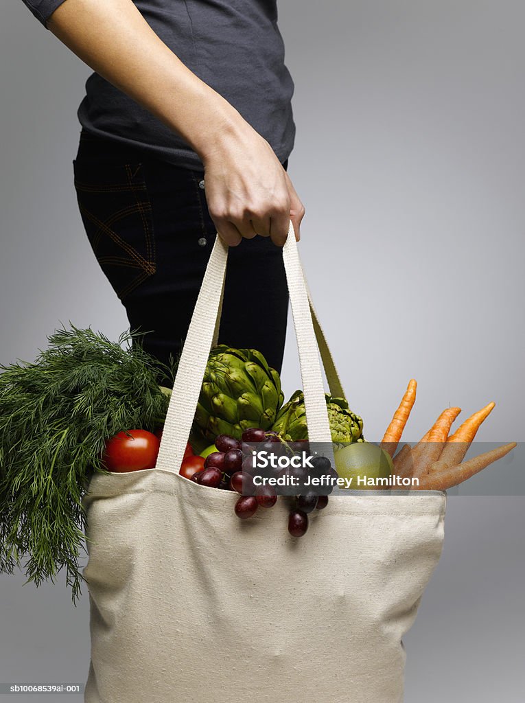 Woman holding grocery bags containing vegetables, mid section  Vegetable Stock Photo