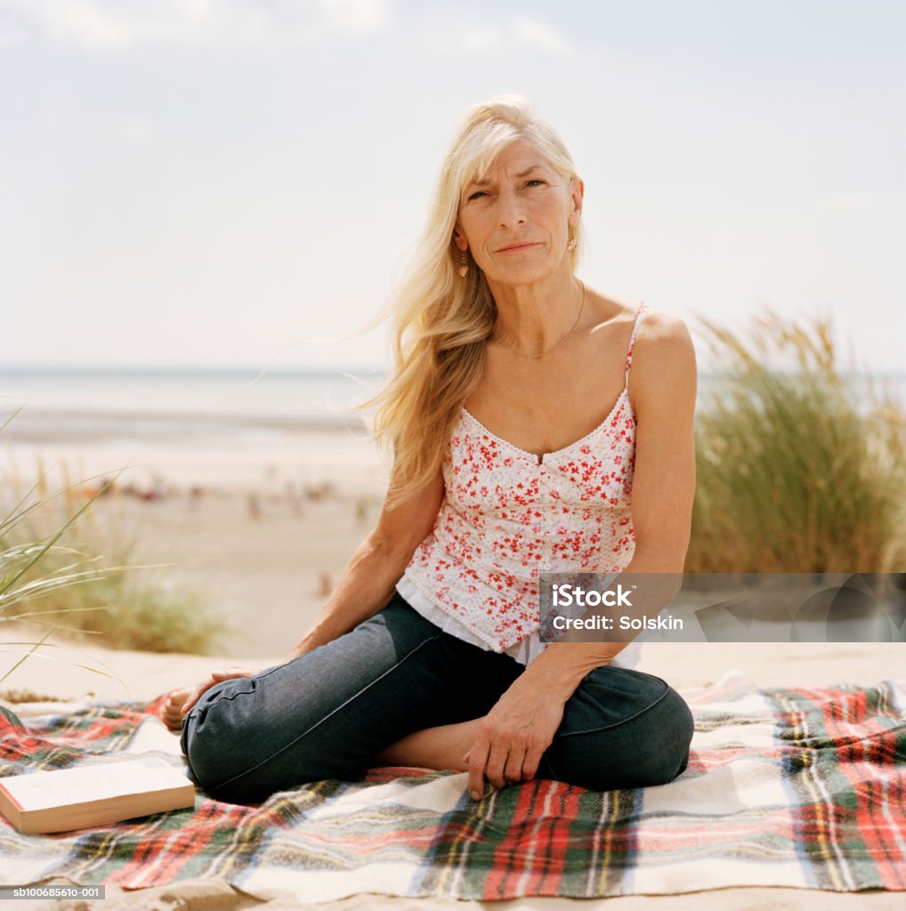 United Kingdom, Rye, Camber Sands, woman sitting on blanket at beach, portrait  One Woman Only Stock Photo