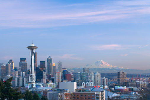 A scenic cityscape of the Seattle with a snowy mountain and dark clouds in the background