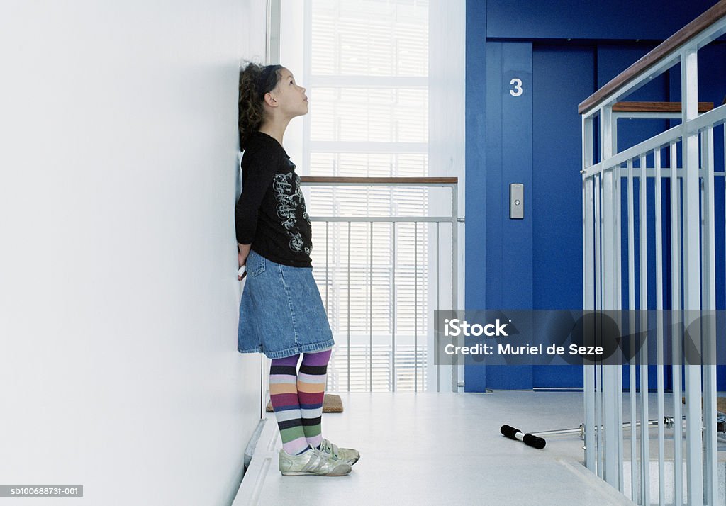 Girl (10-11) leaning on wall in corridor, side view - Foto de stock de 10-11 años libre de derechos
