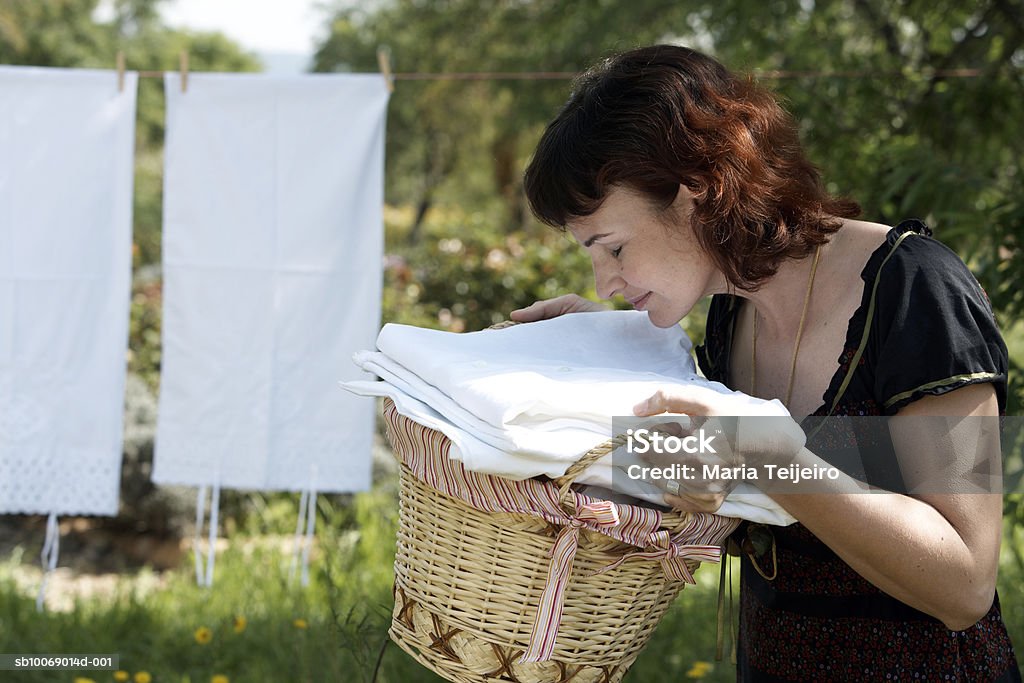 Mujer de mediana edad oliendo fleshly lavar la ropa en el jardín - Foto de stock de Oler libre de derechos