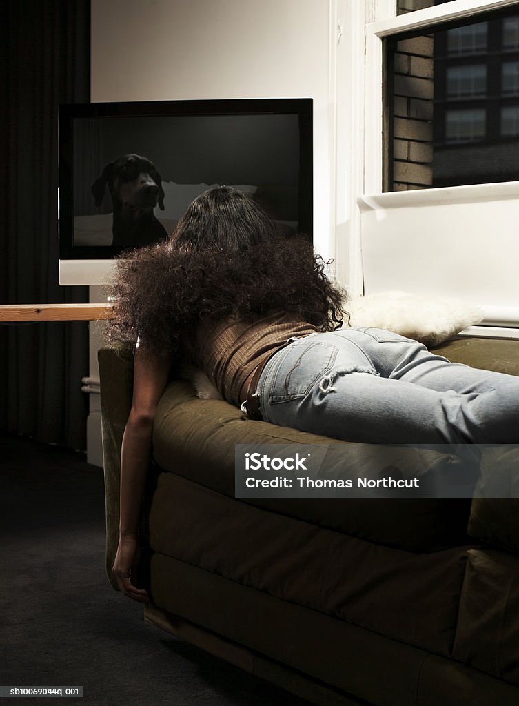 Young woman lying en el sofá mientras mira televisión - Foto de stock de Televisión libre de derechos
