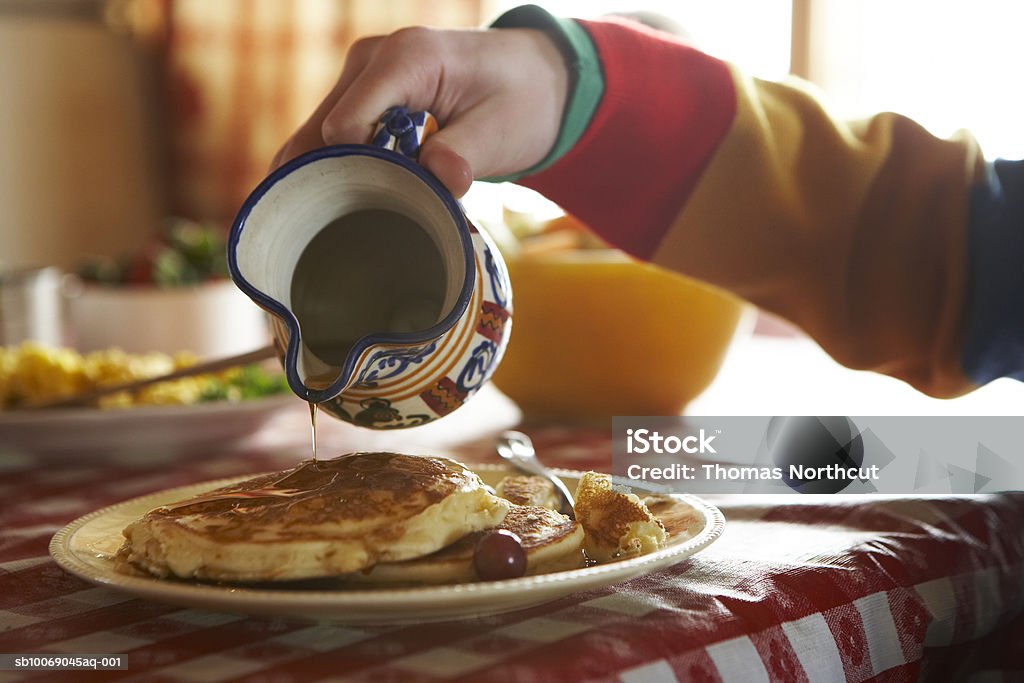 Teenage boy (13-14) pouring syrup on pancakes  14-15 Years Stock Photo