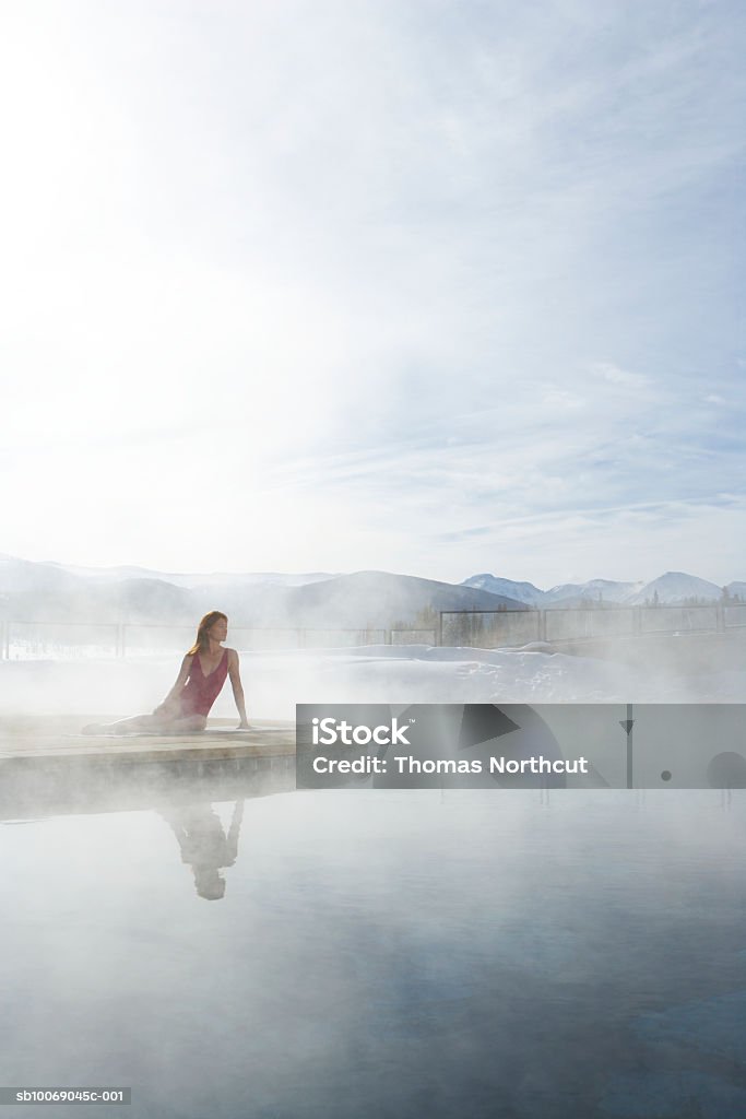 Joven mujer sentada junto a la piscina - Foto de stock de Fuente Termal libre de derechos