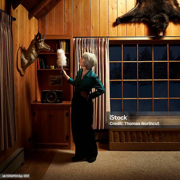 Mature Woman Dusting With Feather Duster Stock Photo - Download Image Now - Housework, Cleaning, Dusting