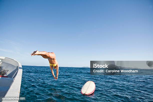 Mid Adult Woman Jumping From Boat Into Sea Stock Photo - Download Image Now - Diving Into Water, One Woman Only, 30-39 Years