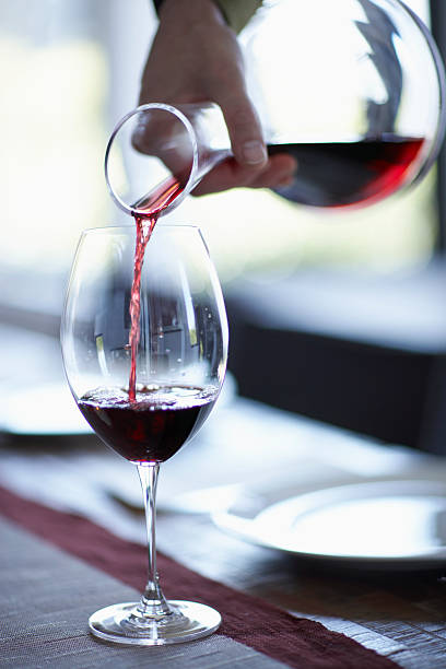 person pouring wine from decanter into wine glass, close-up - carafe decanter glass wine photos et images de collection