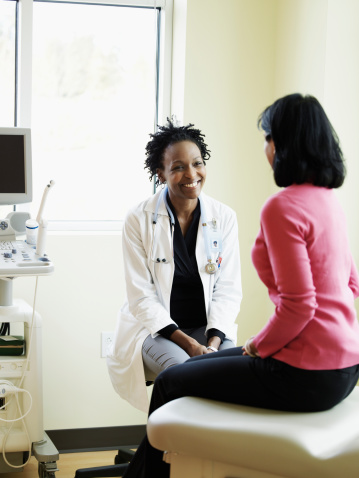 Female doctor talking to woman in exam room, smiling photo