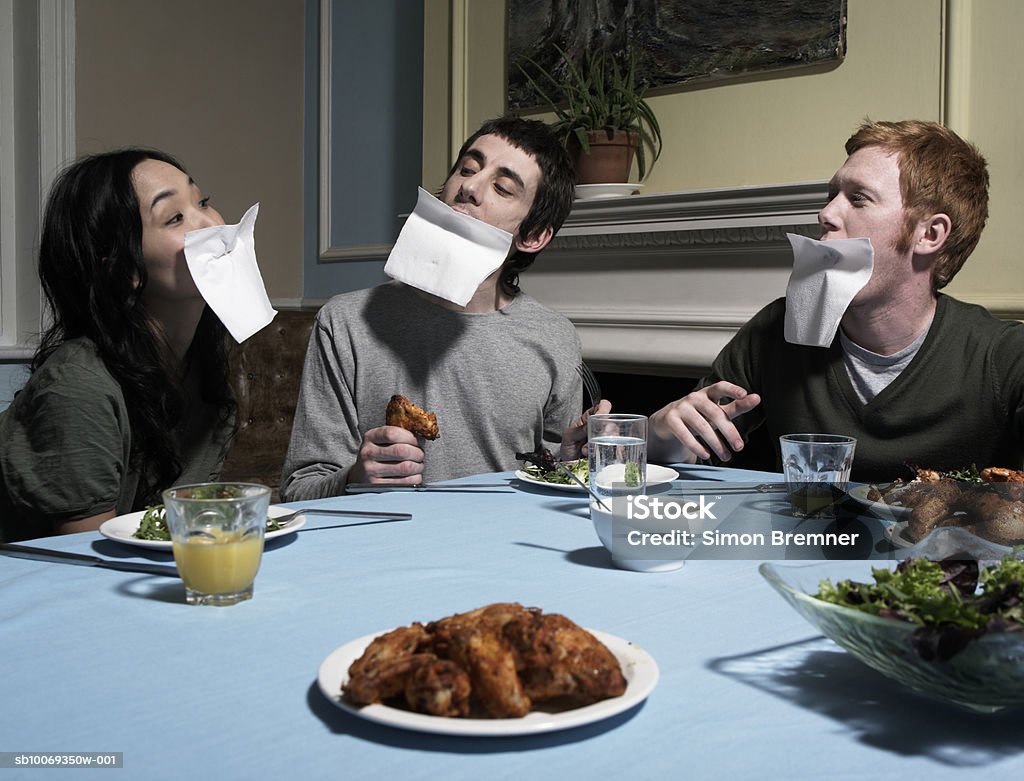 Three people with napkins over faces, at dining table  Bizarre Stock Photo