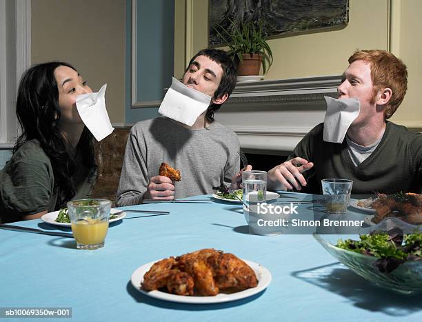 Three People With Napkins Over Faces At Dining Table Stock Photo - Download Image Now