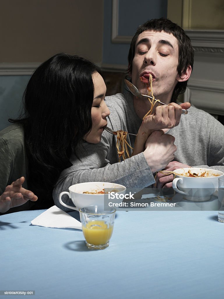 Couple eating spaghetti at dining room table  Couple - Relationship Stock Photo