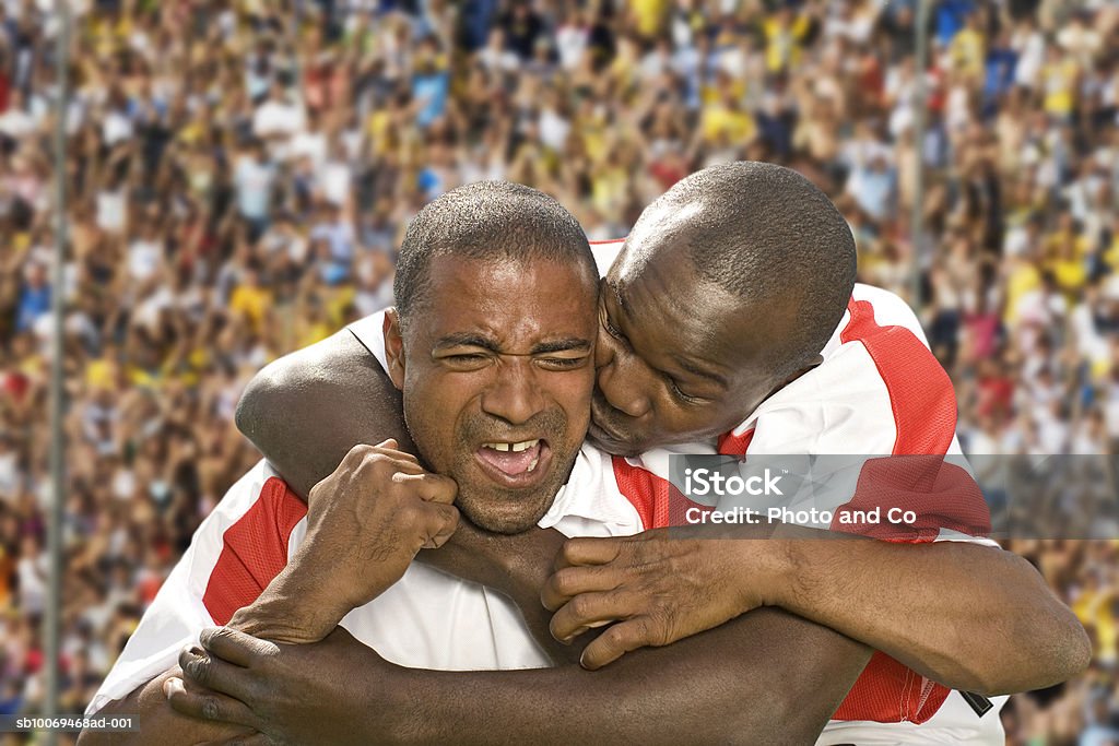 Two male soccer players embracing in stadium - Foto de stock de Jugador de fútbol libre de derechos