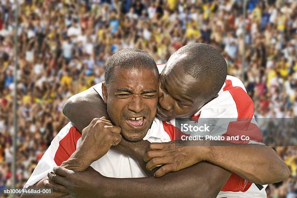 Two Male Soccer Players Embracing In Stadium Foto de stock y más banco de imágenes de Jugador de fútbol - Jugador de fútbol, Abrazar, Celebración - Ocasión especial