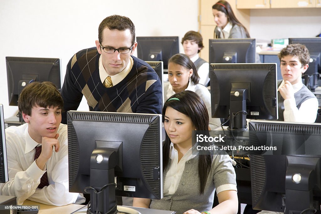 Lehrer mit Schule Kinder (14 – 19) arbeitet in computer lab - Lizenzfrei Bildung Stock-Foto