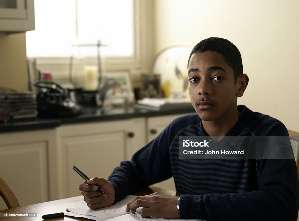 Portrait of boy (12-13) doing homework at kitchen table, portrait  Child Stock Photo