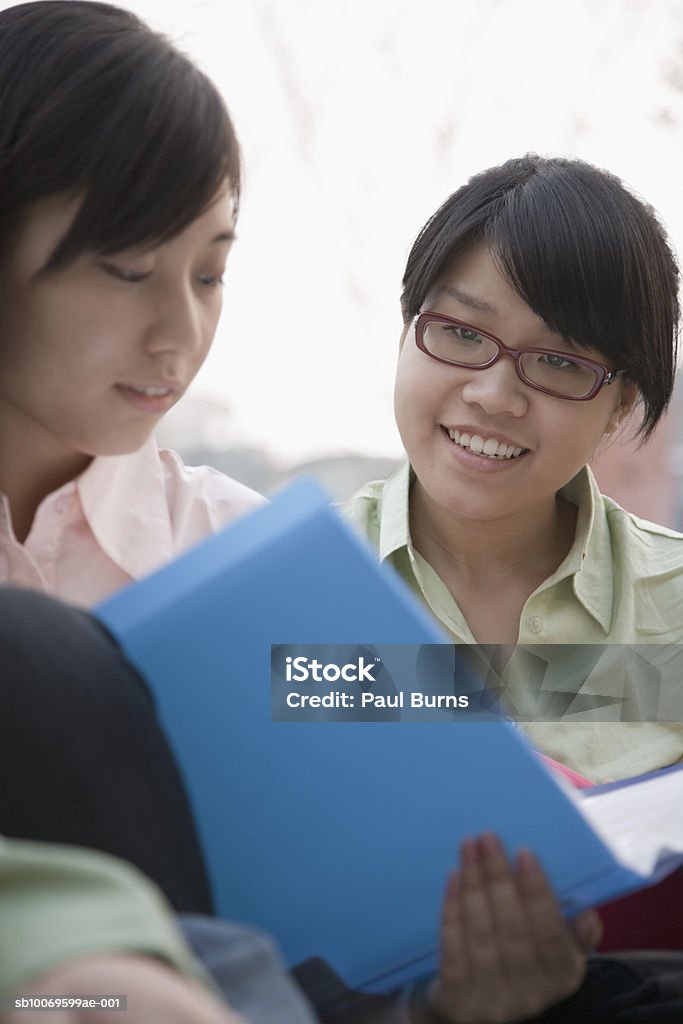 Two university students looking at book, smiling - Foto stock royalty-free di 20-24 anni