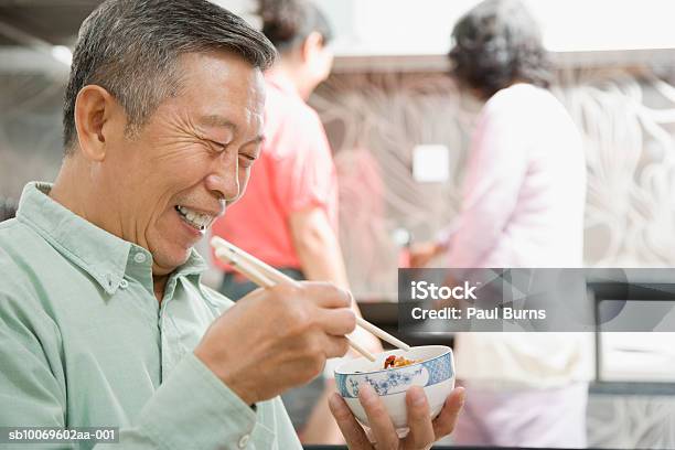 Senior Man Eating With Chopsticks Women In Background Stockfoto und mehr Bilder von 40-44 Jahre